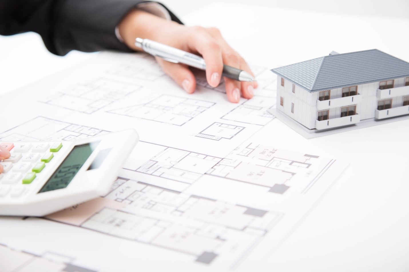 Person reviewing drawing plans for a condominium complex with a pen and calculator in hand